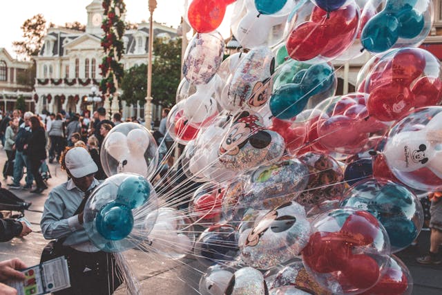 person holding disney-themed balloons